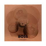 A square metallic rose gold box for BOSS The Scent, featuring a subtle circular floral pattern with the BOSS logo and the text 'BOSS THE SCENT' in black at the bottom.